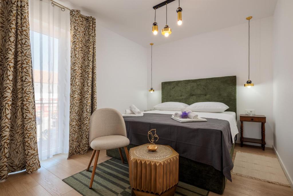 a bedroom with a bed with a chair and a table at Villa Mare's in Primošten