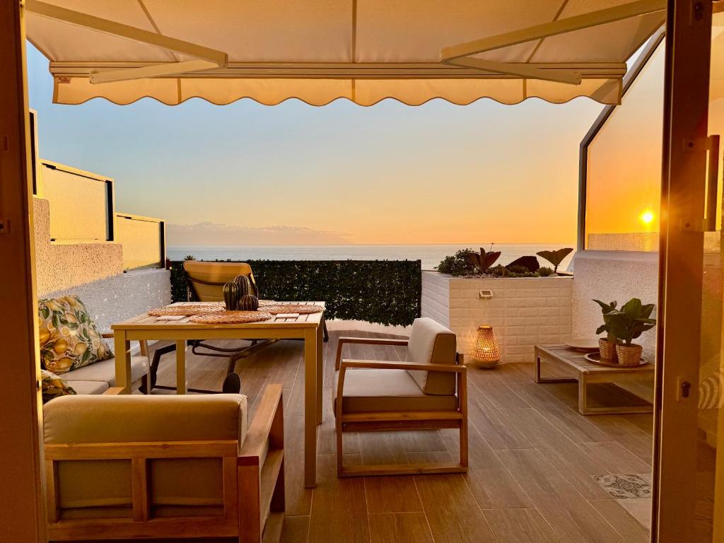 eine Terrasse mit Tisch und Stühlen und Blick auf das Meer in der Unterkunft Casa Oceanico Los Gigantes in Acantilado de los Gigantes