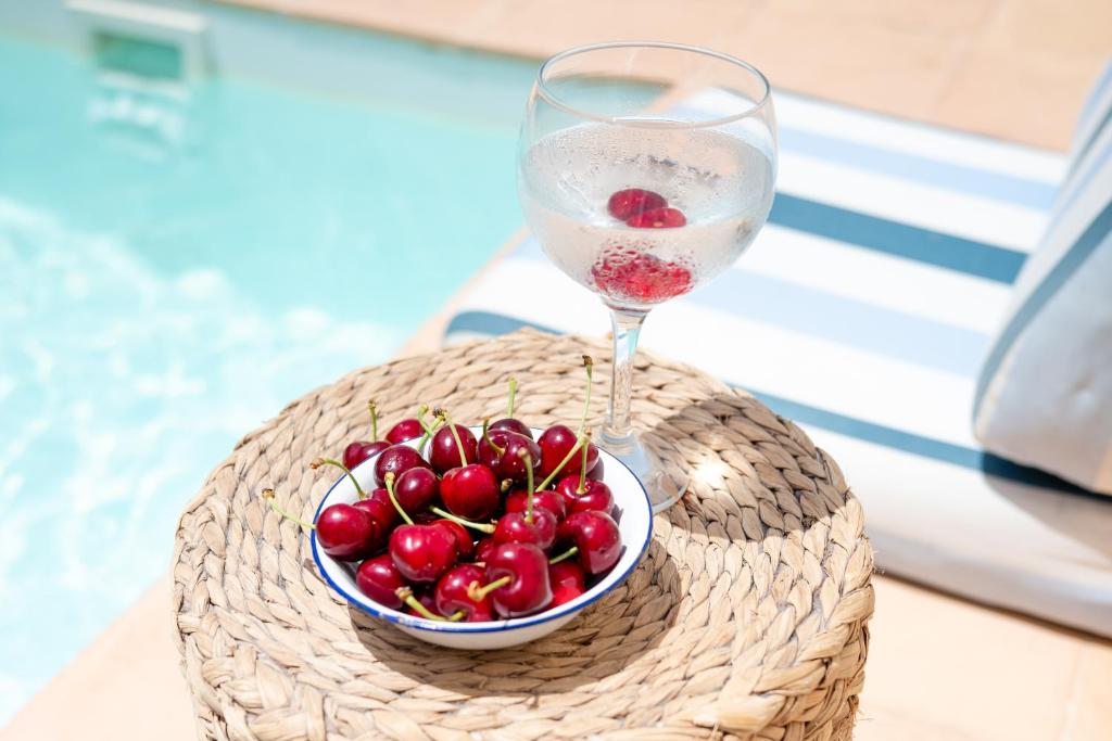 eine Schale Kirschen und ein Glas Wein auf einem Tisch in der Unterkunft Alojamiento rural La Mula en pleno corazón de la montaña de Alicante in Patró