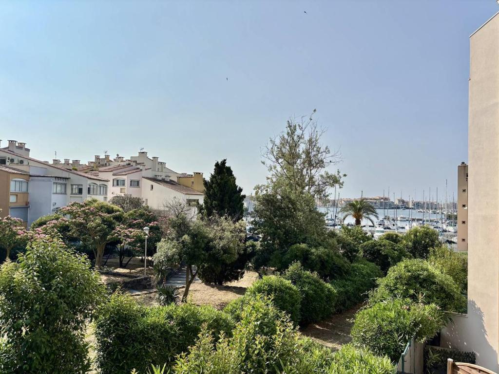 - une vue sur une cour avec des arbres et des maisons dans l'établissement Port, jardins, clim, calme, centre Cap d'Agde - FR-1-723-43, au Cap d'Agde