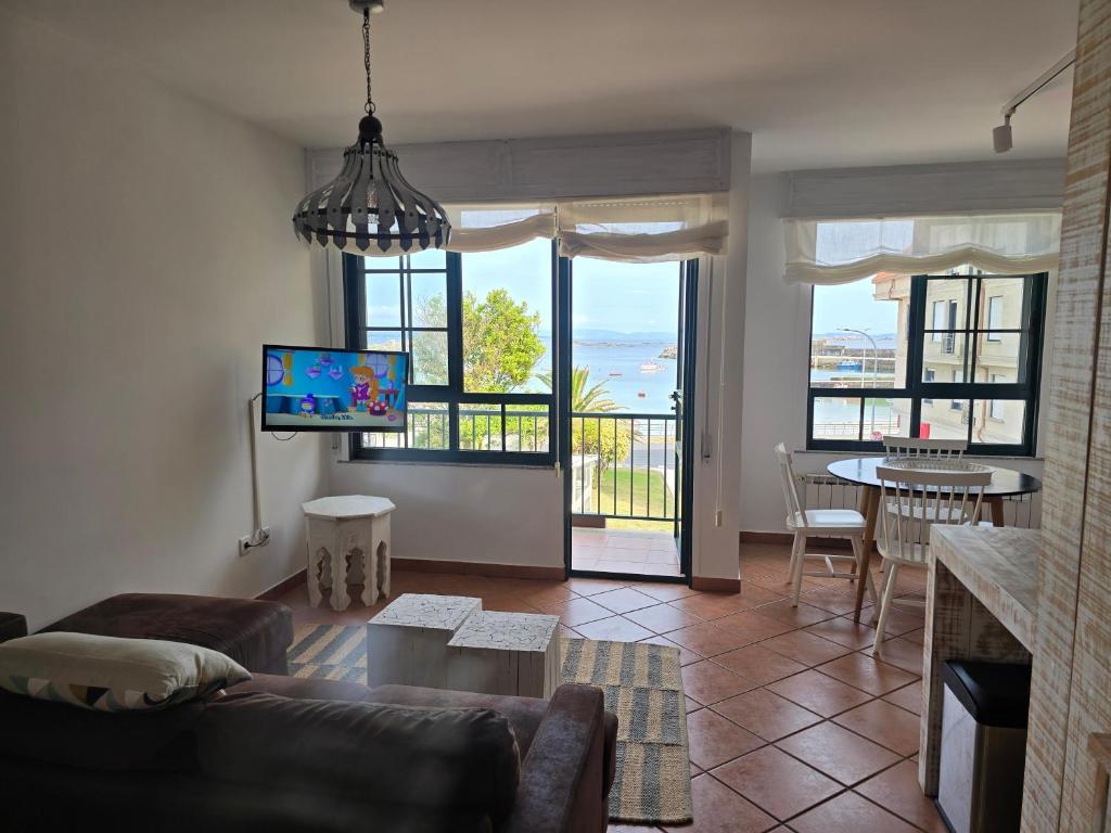 a living room with a couch and a tv and some windows at Winahost Salvora en Primera Línea de Mar in Ribeira