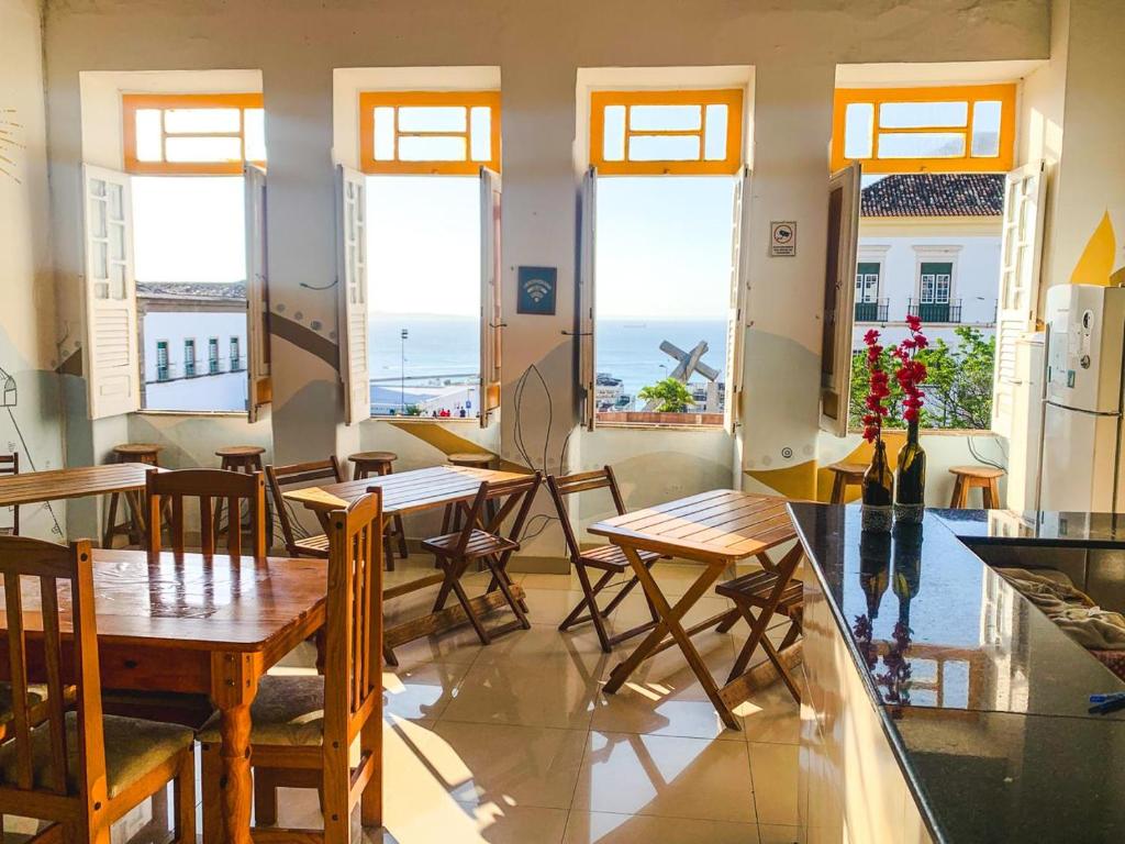 a dining room with tables and chairs and windows at Pousada Morro de Sao Paulo in Salvador