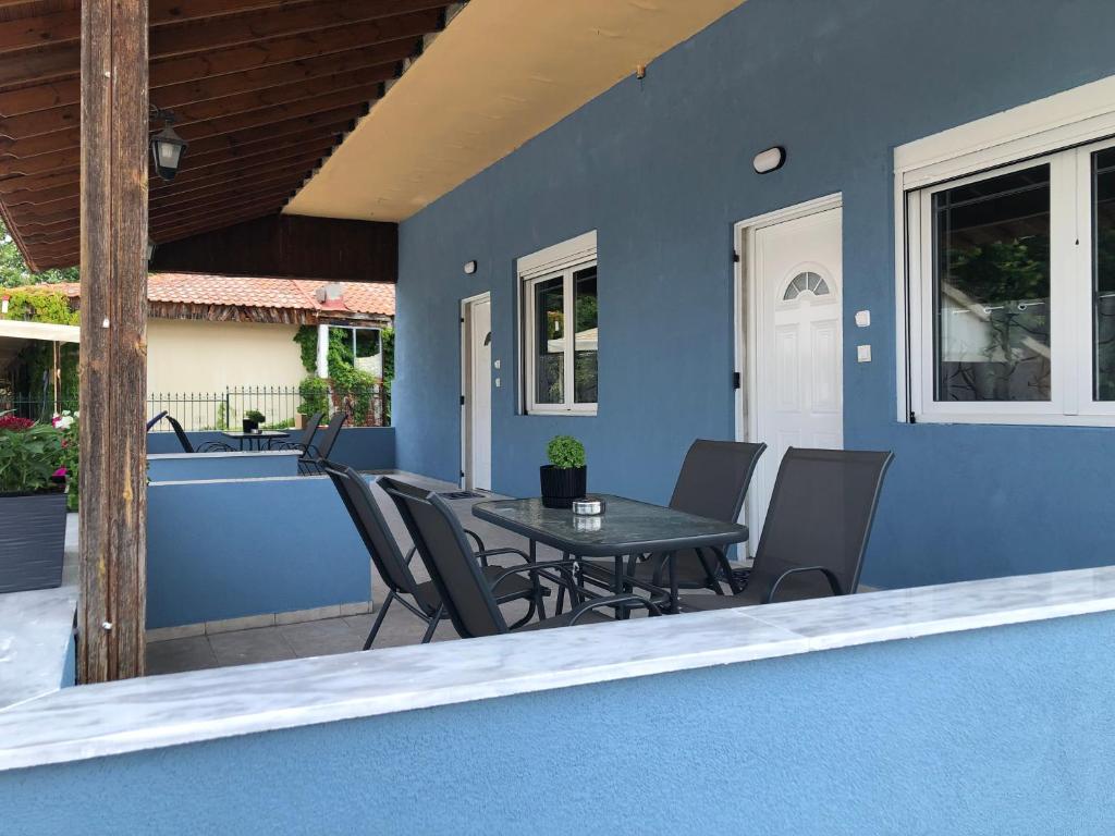 a patio with a table and chairs on a blue wall at Fotis Apartments Palaiokomi in Palaiokómi
