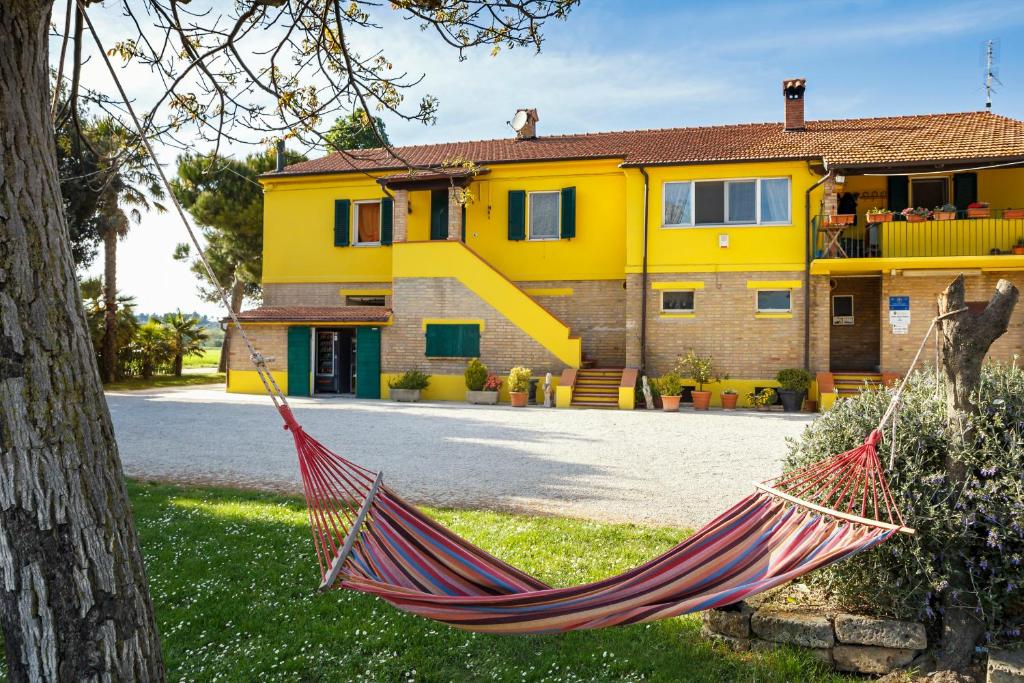 a red hammock in front of a yellow house at B&B Centro Ippico Andrea in Porto Recanati