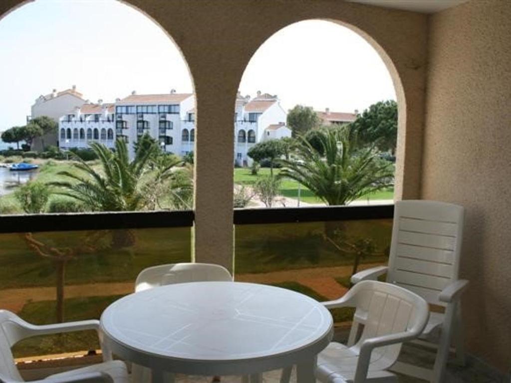 une table et des chaises blanches dans une chambre avec fenêtres dans l'établissement Appartement 4 pers - Le Barcarès - Piscine, Parkings, Terrains de Sport, Fitness - FR-1-195-25, au Barcarès