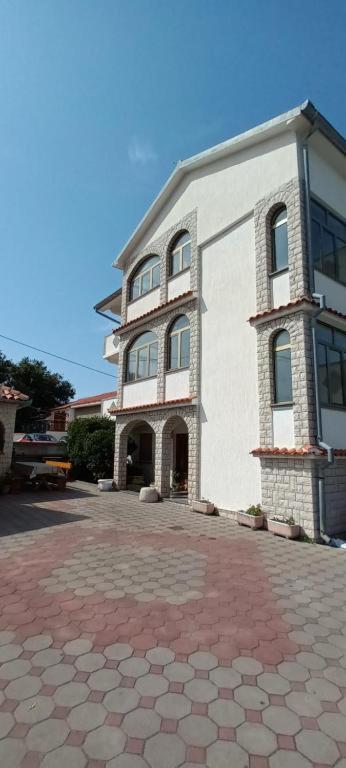 a large white building on a brick road at Apartments DEXI in Banjol