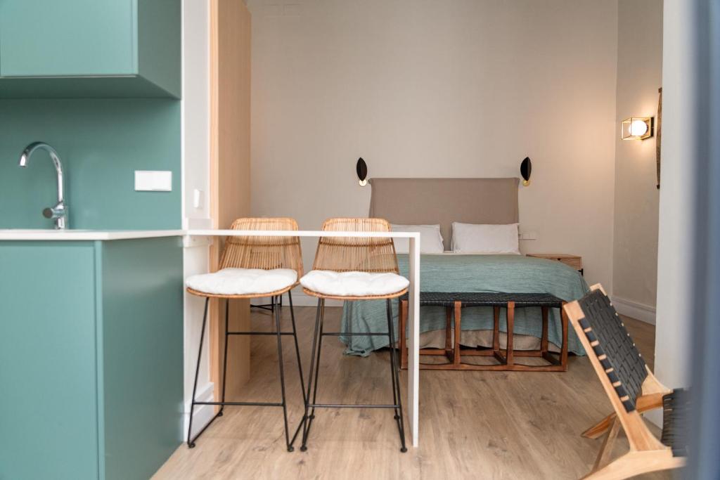 a kitchen with a table with stools and a bed at Honest Sevilla Apartments in Seville