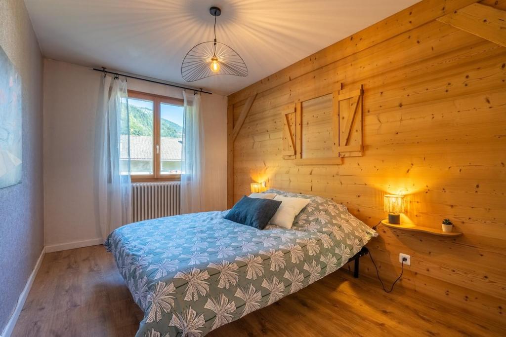 ein Schlafzimmer mit einem Bett und einer Holzwand in der Unterkunft Proche centre Thônes, Apt Cosy entre Lac&Montagnes in Thônes