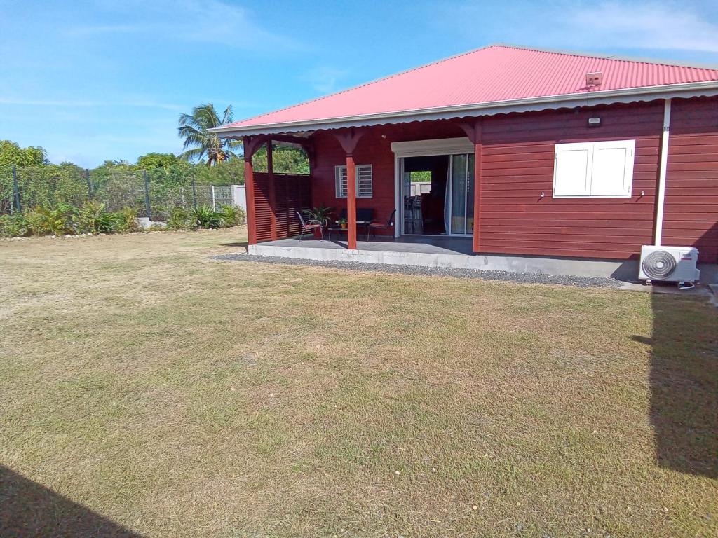 a red house with a large yard in front of it at Villa LANDREVA in Anse-Bertrand
