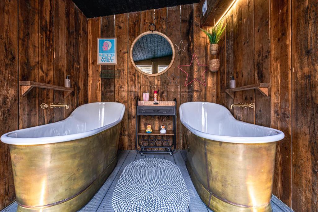 a bathroom with two tubs in a wooden wall at Ffolkes in Hillington