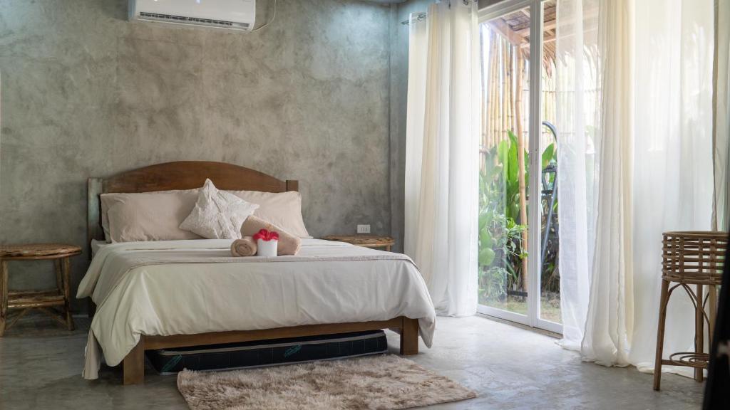 a bedroom with a bed and a large window at Villa Rosa Siargao in General Luna