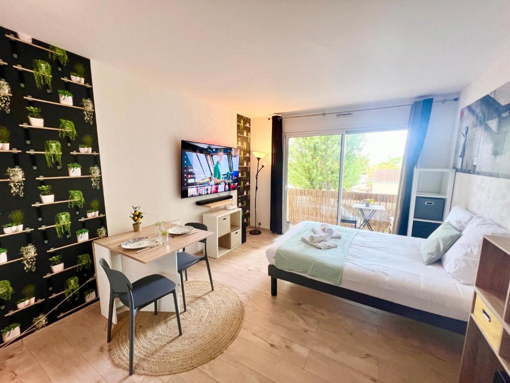 a bedroom with a bed and a table and a television at L'Estival, Royan in Royan