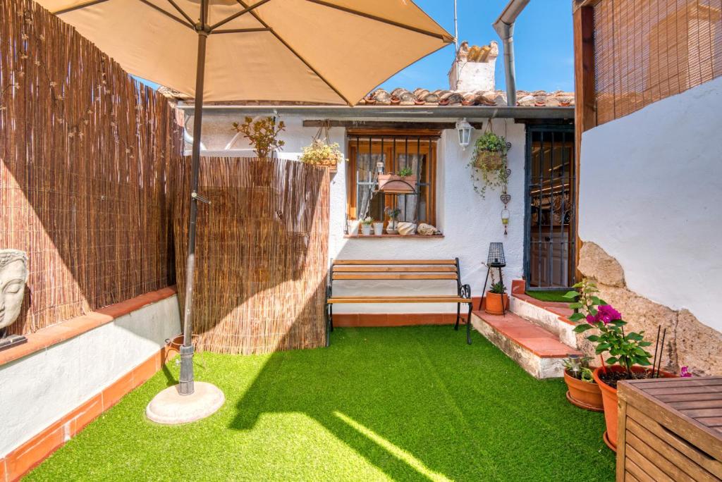 a small backyard with an umbrella and grass at Casa Trinidad in Denia
