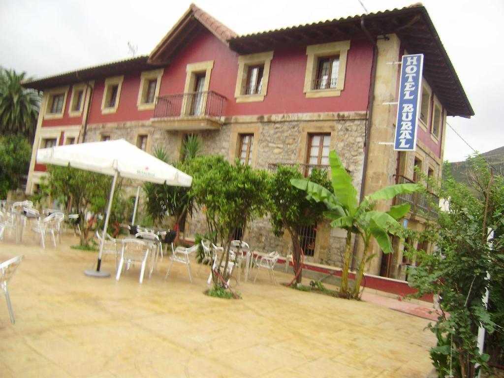 a hotel with tables and chairs in front of a building at Hotel Rural Las Palmeras Muskiz in Muskiz