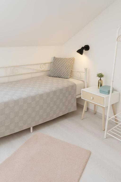 a white bedroom with a bed and a table at xgeschlossen in Hirschaid