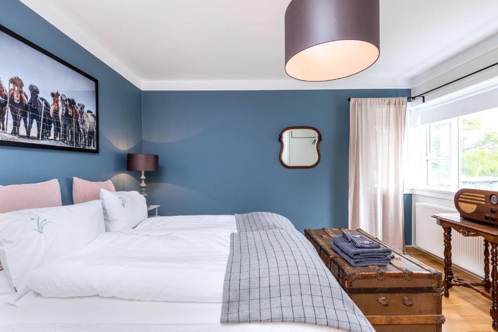 a blue bedroom with a white bed and a window at Freyja Guesthouse & Suites in Reykjavík