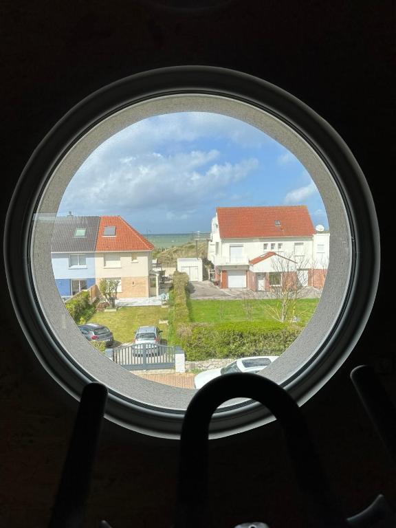 une fenêtre ronde avec vue sur une maison dans l'établissement L œil de sangatte, à Sangatte