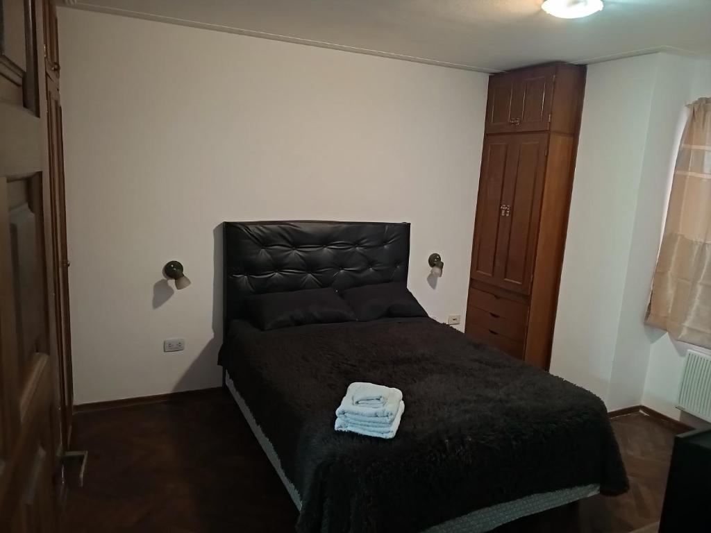 ein Schlafzimmer mit einem schwarzen Bett mit schwarzem Kopfteil in der Unterkunft Leo IV salta 636 4F in San Fernando del Valle de Catamarca