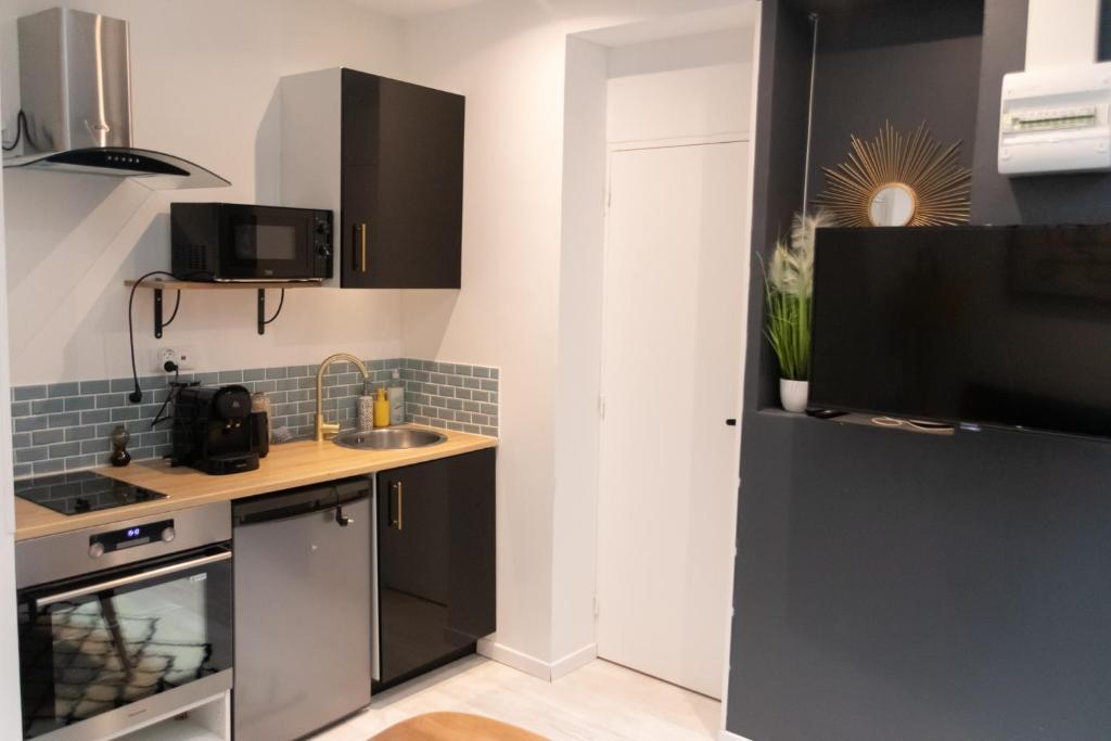 a kitchen with black cabinets and a sink at Le Nid Perché in Amiens