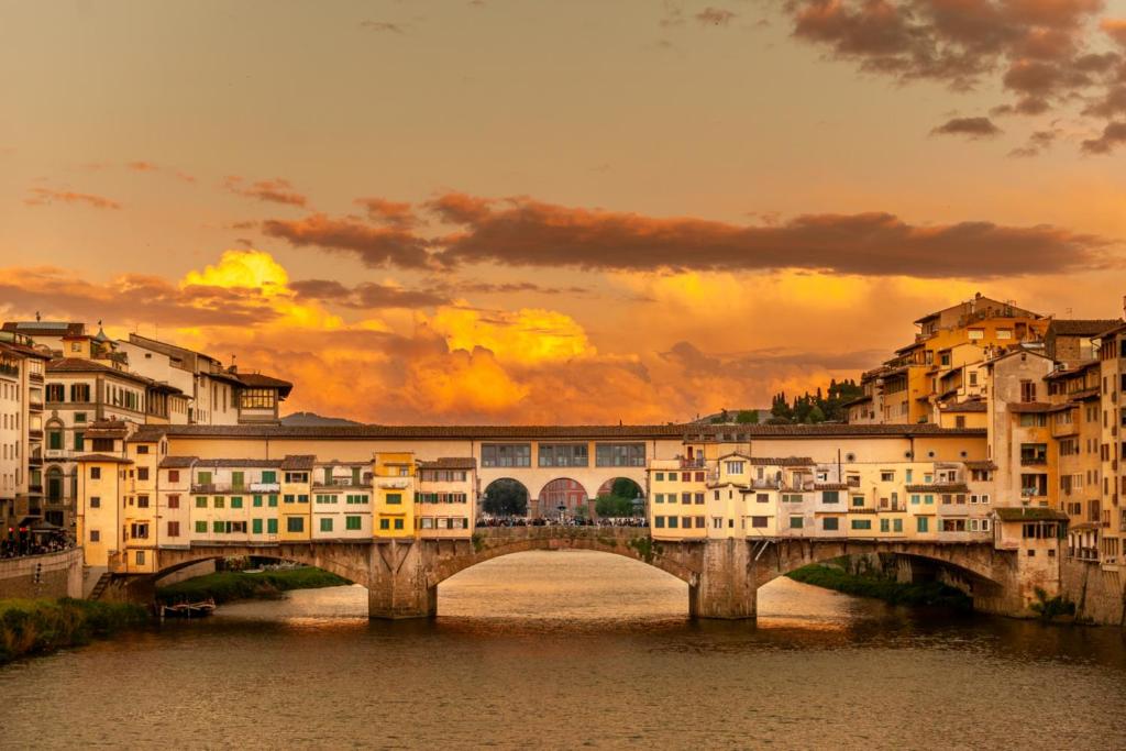 a bridge over a river in a city with buildings at Oriani Central Rooms in Florence