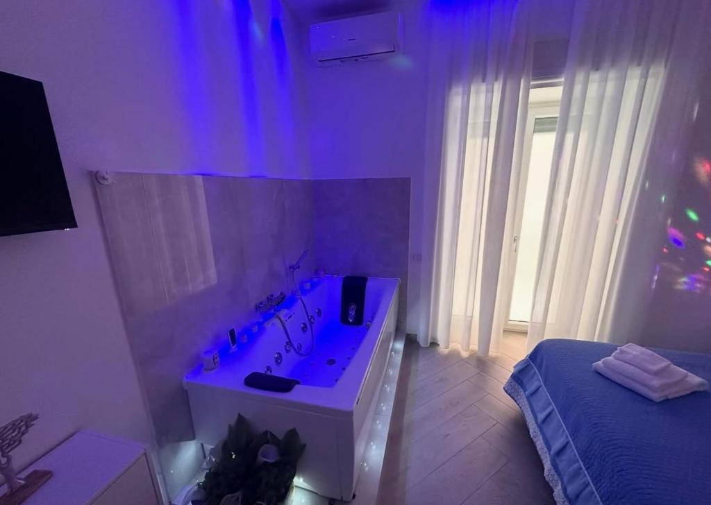 a white bathroom with a tub and a bed at Suite Eleven in Naples