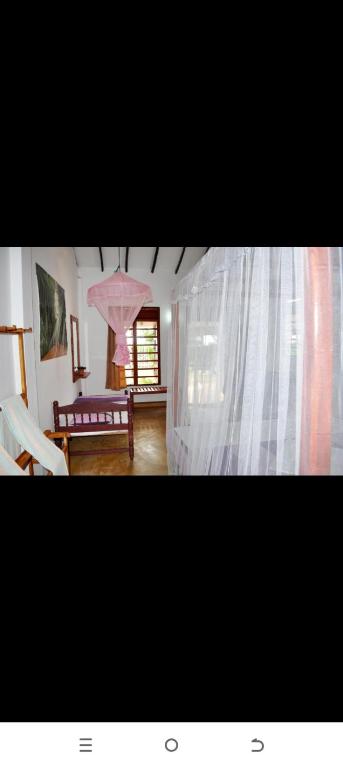 Una sala de estar con una sombrilla rosa y un sofá. en Dilena Beach Inn, en Tangalle
