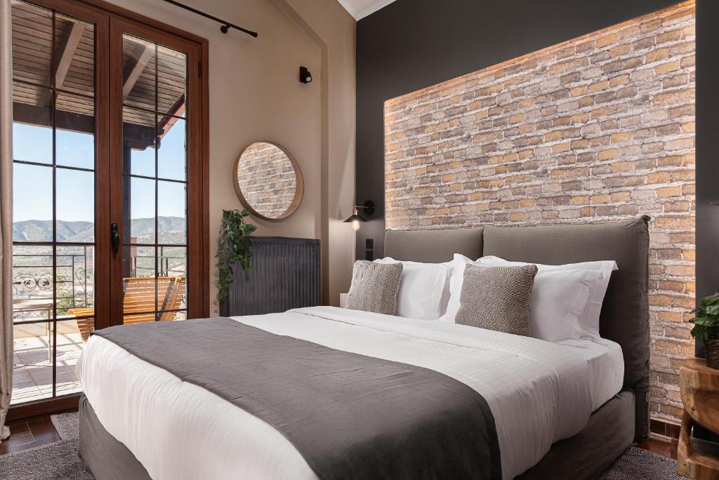 a bedroom with a large bed and a brick wall at Tilemachos by GM Luxury Suites Kalavryta in Kalavrita