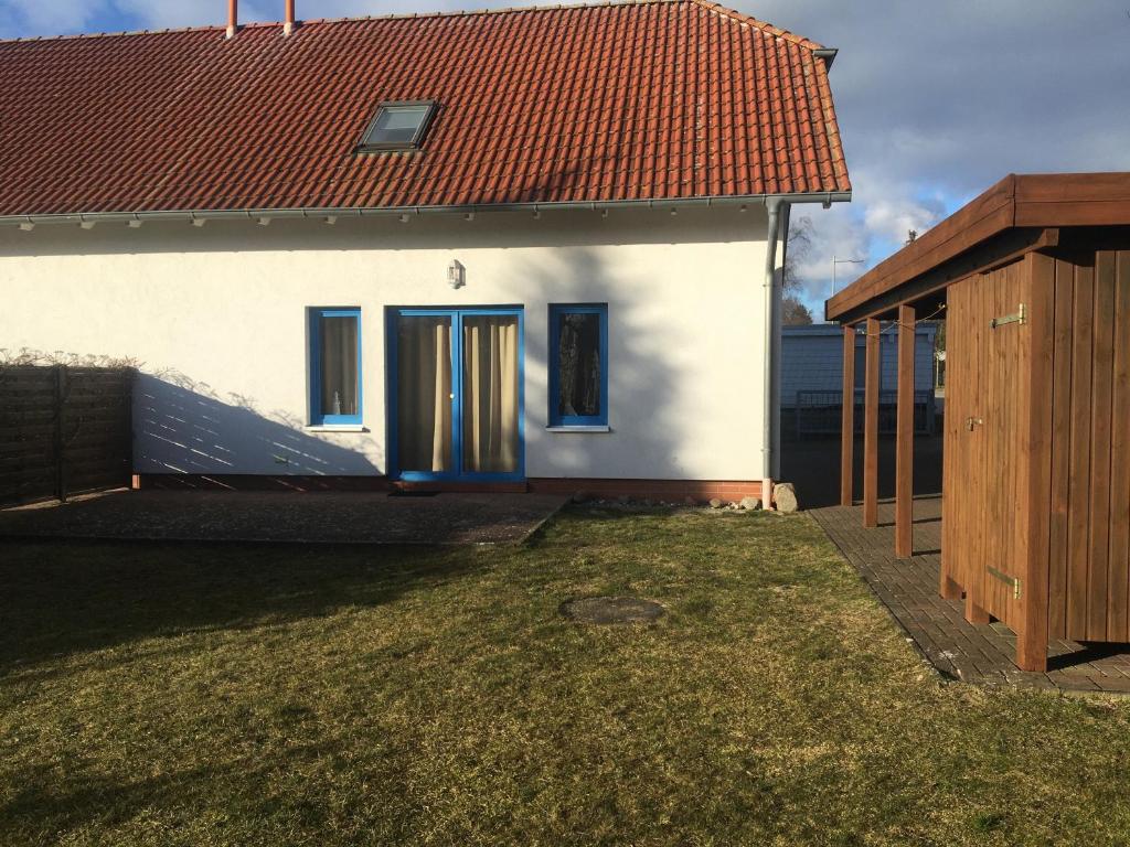 a white house with a red roof and blue doors at Zinnowitz, Kneippstr 24 b in Zinnowitz