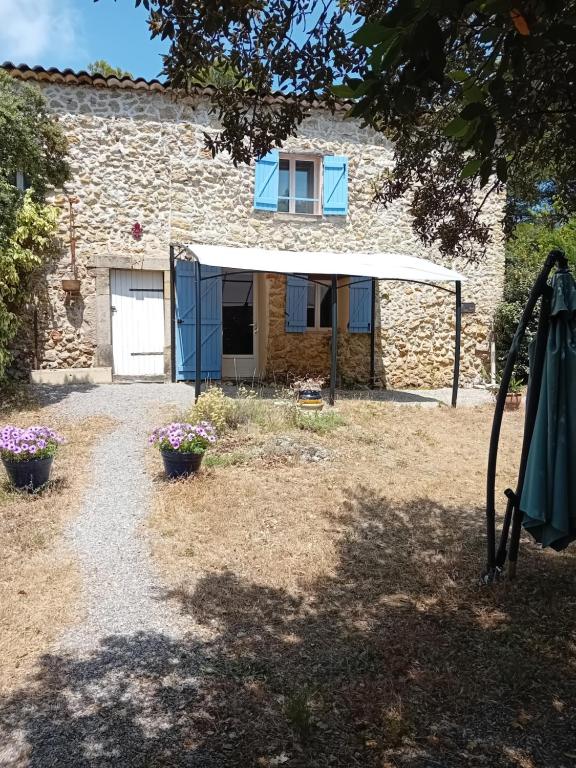une maison en pierre avec une fenêtre bleue et un bâtiment dans l'établissement la bergerie, à Tourtour