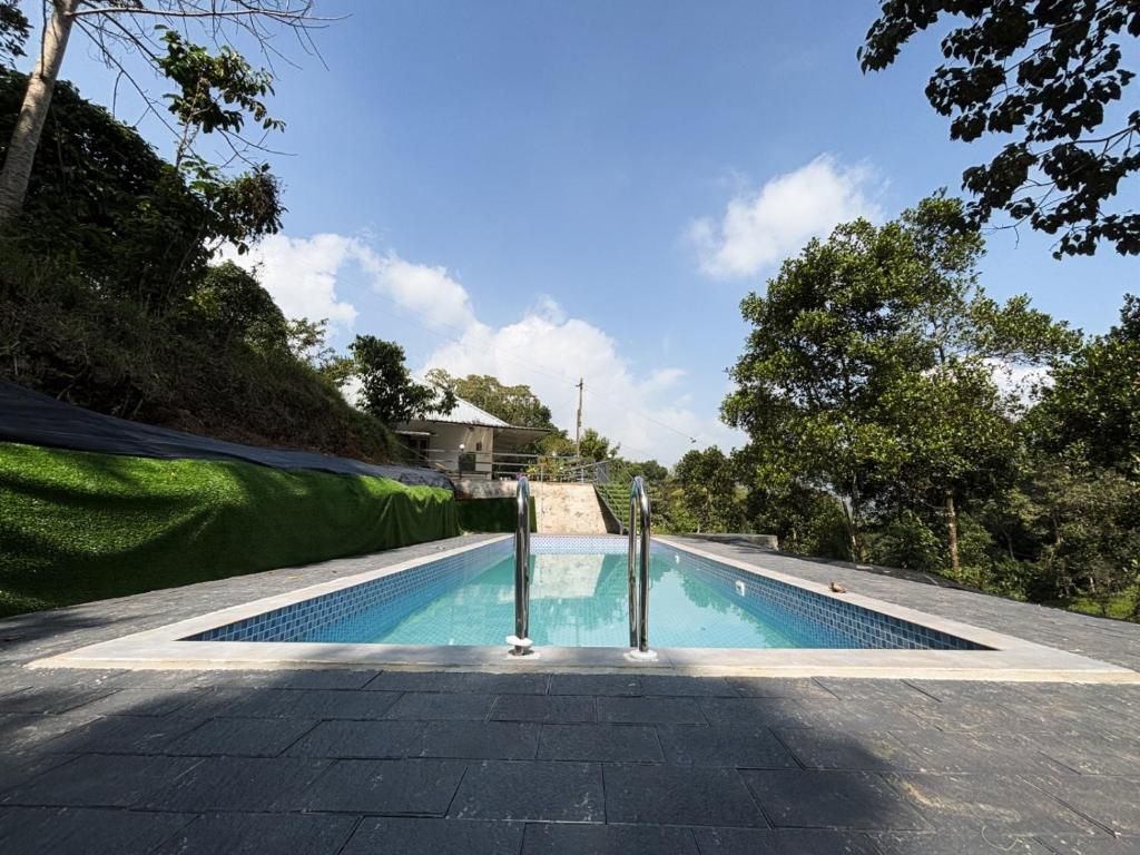 una piscina rodeada de una valla verde. en Eco Hills Private Pool Villa, en Munnar