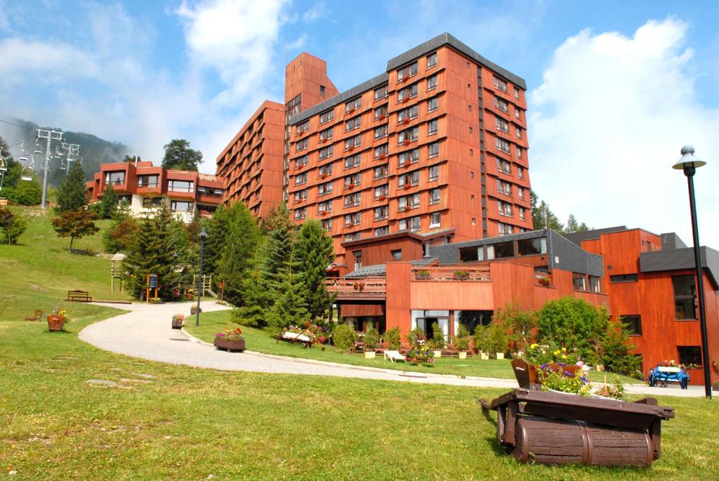 un grand bâtiment rouge avec un parc en face dans l'établissement Azureva Les Karellis - Skipass Inclus!, à Montricher-le-Bochet
