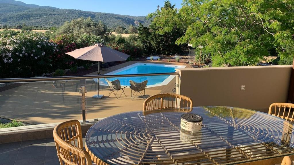 a table with chairs and an umbrella on a patio at Villa Polyxeni Magnolia 150m from the sea in Politiká