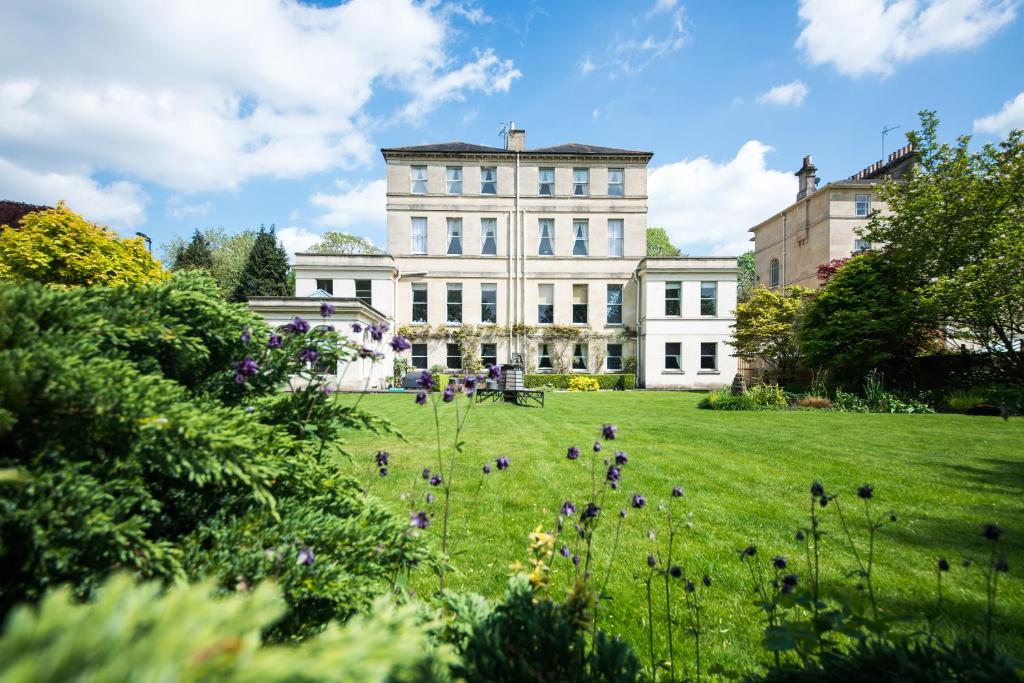 a large white house with a green lawn with flowers at The Ayrlington Guesthouse in Bath