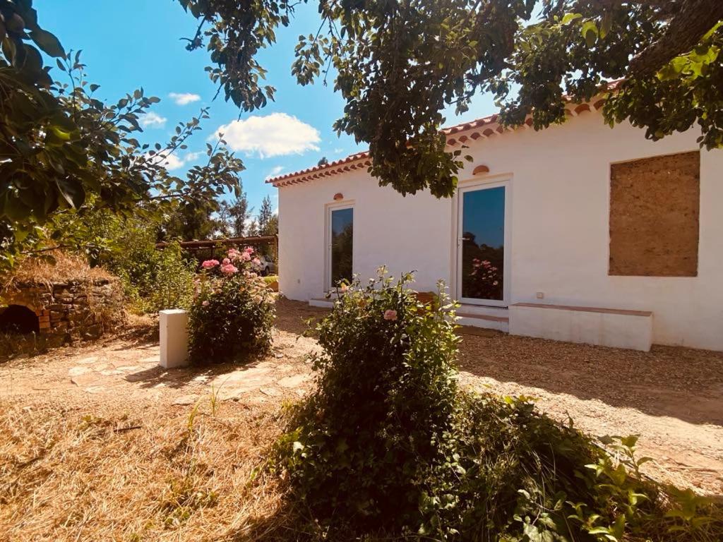 a white house with flowers in front of it at Monte das Raizes in São Teotónio