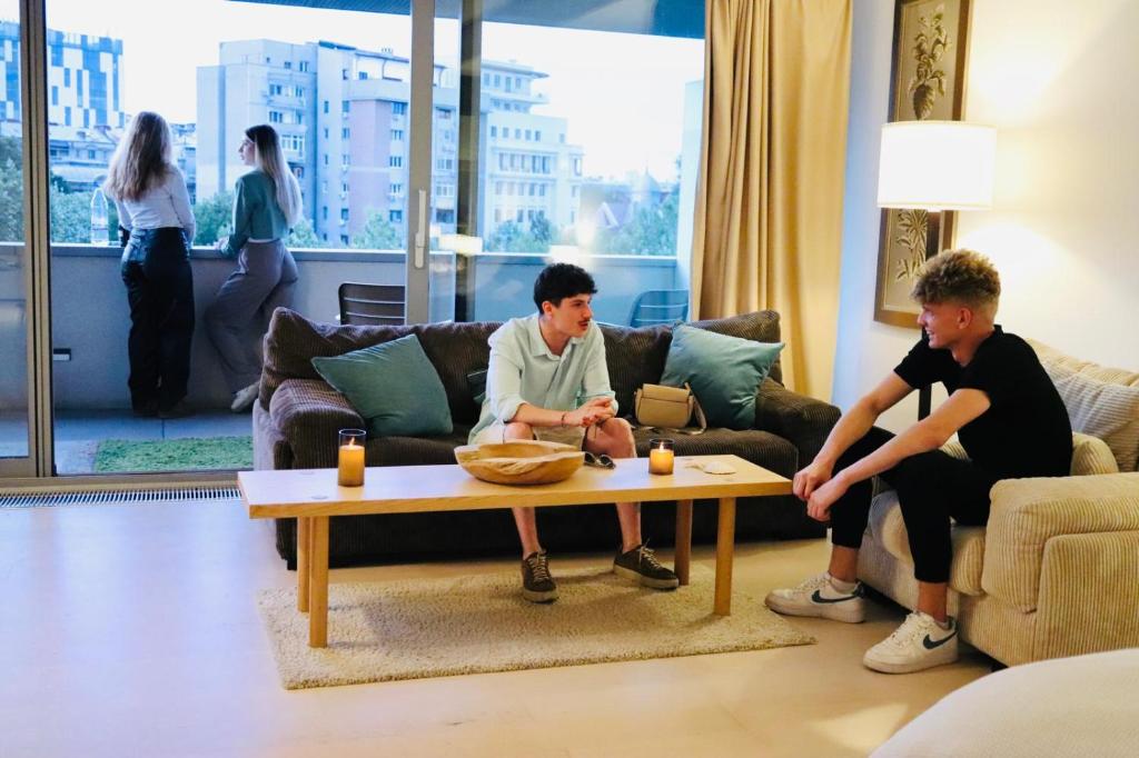 two men sitting around a coffee table in a living room at Vernescu 4 Luxury Living - Terrace Central Chic in Bucharest