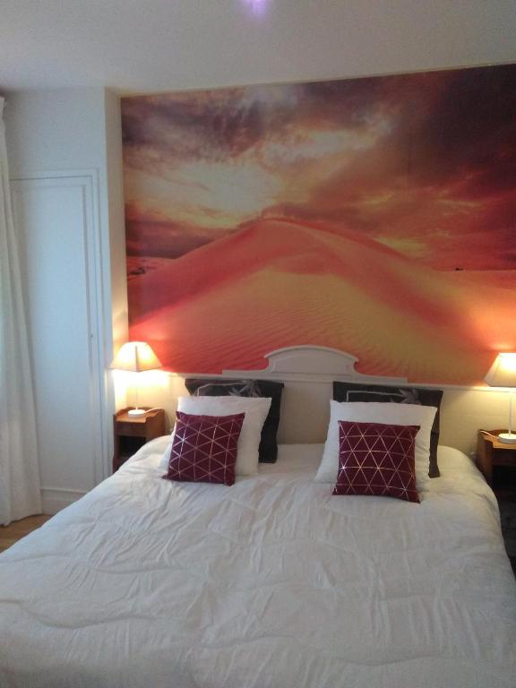a bedroom with a large bed with a painting on the wall at Villa Do Sol Chambre d'Hôtes "La Dune" in Arcachon