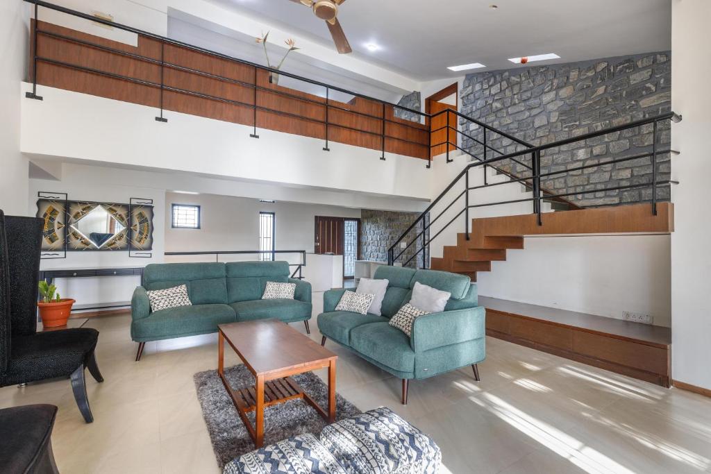 a living room with two couches and a staircase at Grandeur Villa by StayJade Huge Garden 5BHK in Yelahanka