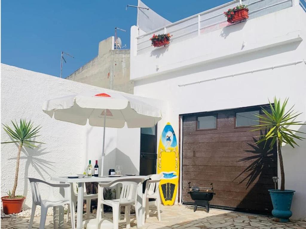 a patio with a table and chairs and an umbrella at Refugio Terrace House Peniche in Atouguia da Baleia