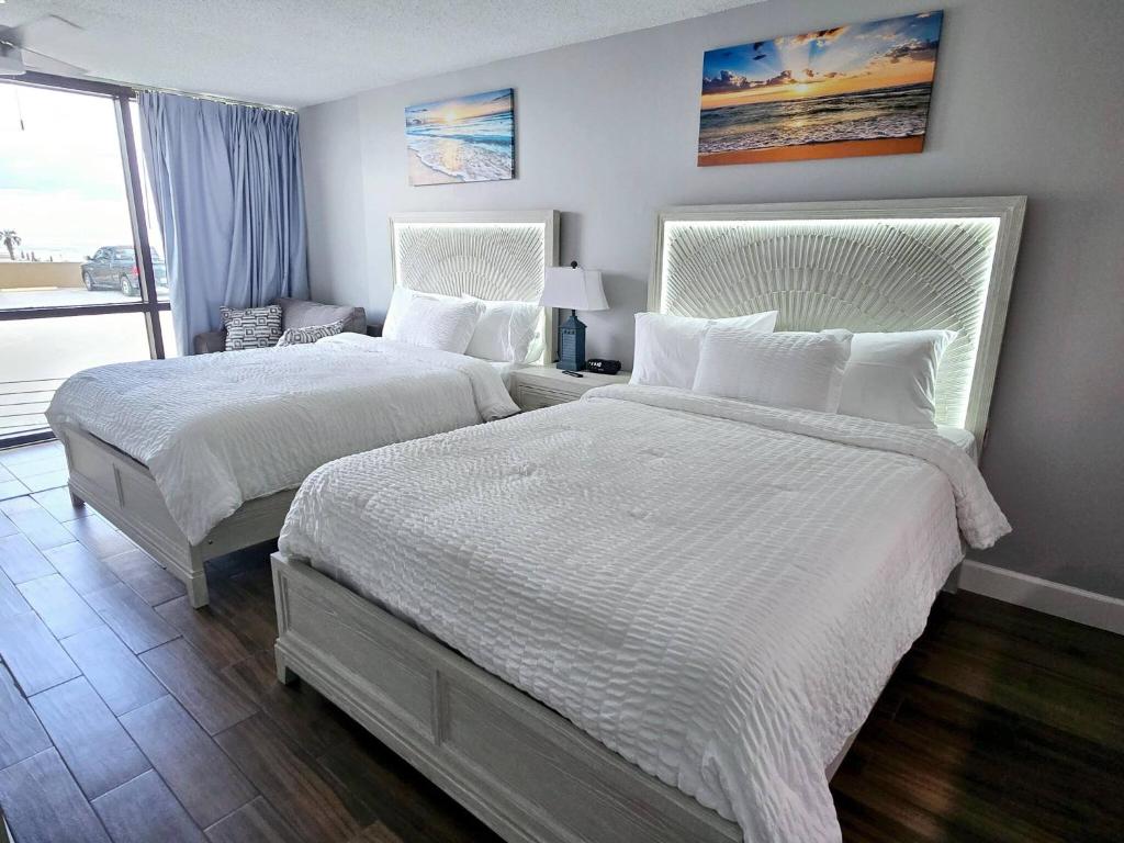 デイトナビーチにあるNew updated Daytona Oceanview w/kitchenette, poolのベッドルーム1室(白いシーツが備わるベッド2台、窓付)
