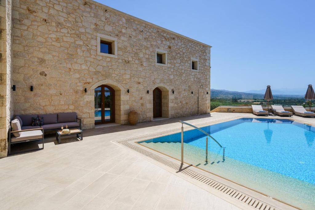 a villa with a swimming pool in front of a building at Spacious Stone Villa with Private Pool, Sea View & Sunset Views in Astérion