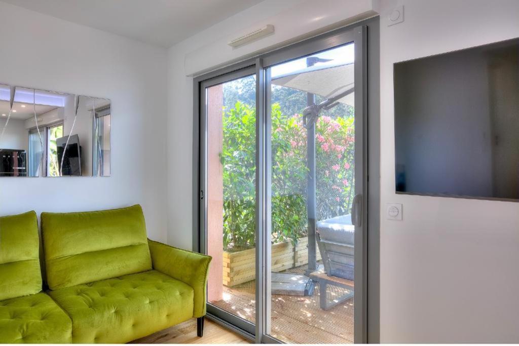 a living room with a green couch and a sliding glass door at Sea View 1B Apartment, Théoule in Théoule-sur-Mer