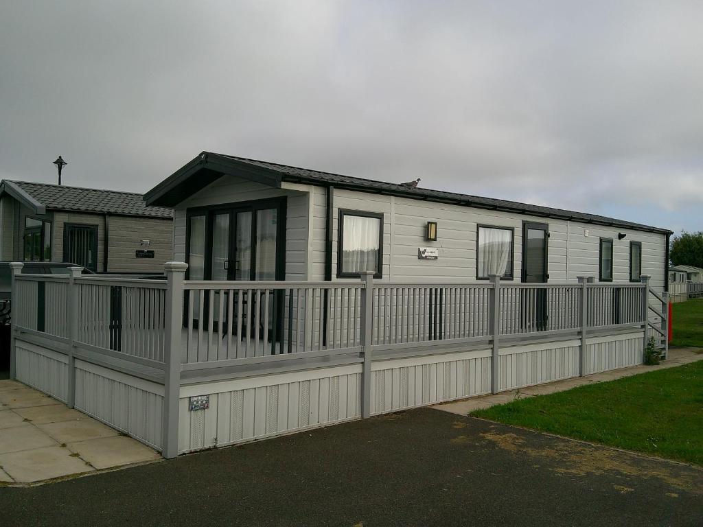 a house with a fence in front of it at Kings Ashington 6 Berth Central Heated Enclosed Veranda in Chapel Saint Leonards