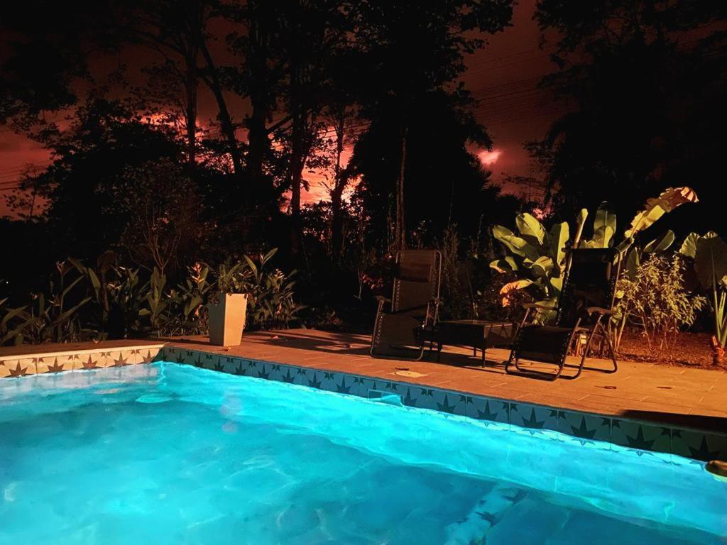 a swimming pool at night with two chairs and a table at Private Cabina at Yoga Center in Ojochal