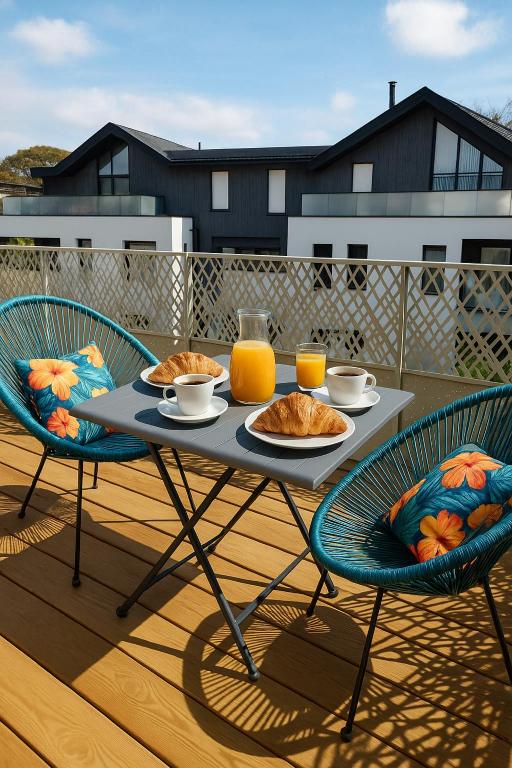 une table avec de la nourriture et deux chaises sur une terrasse dans l'établissement Les reflets de Rivage avec garage privatif - 350m plage, à Concarneau