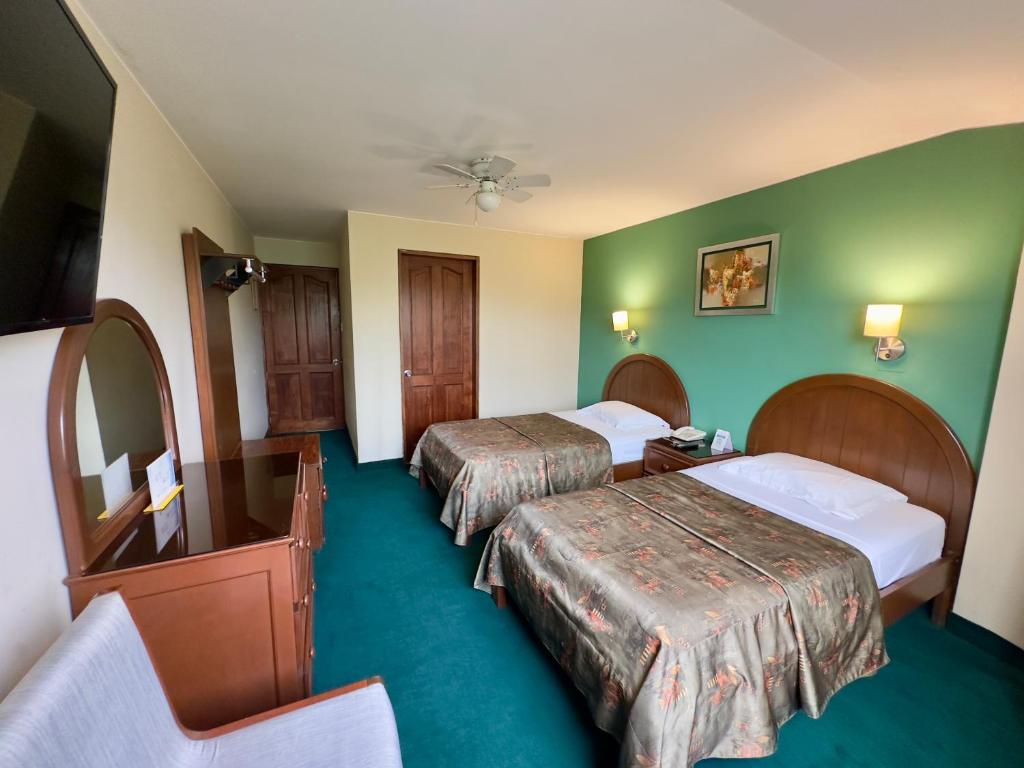 a hotel room with two beds and green walls at Hotel La Molina in Lima