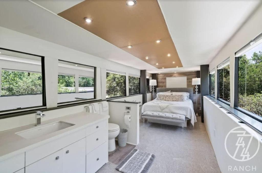a bedroom with a bed and a bathroom with windows at Studio 7744 Ranch Austin Venue and Rentals in Austin
