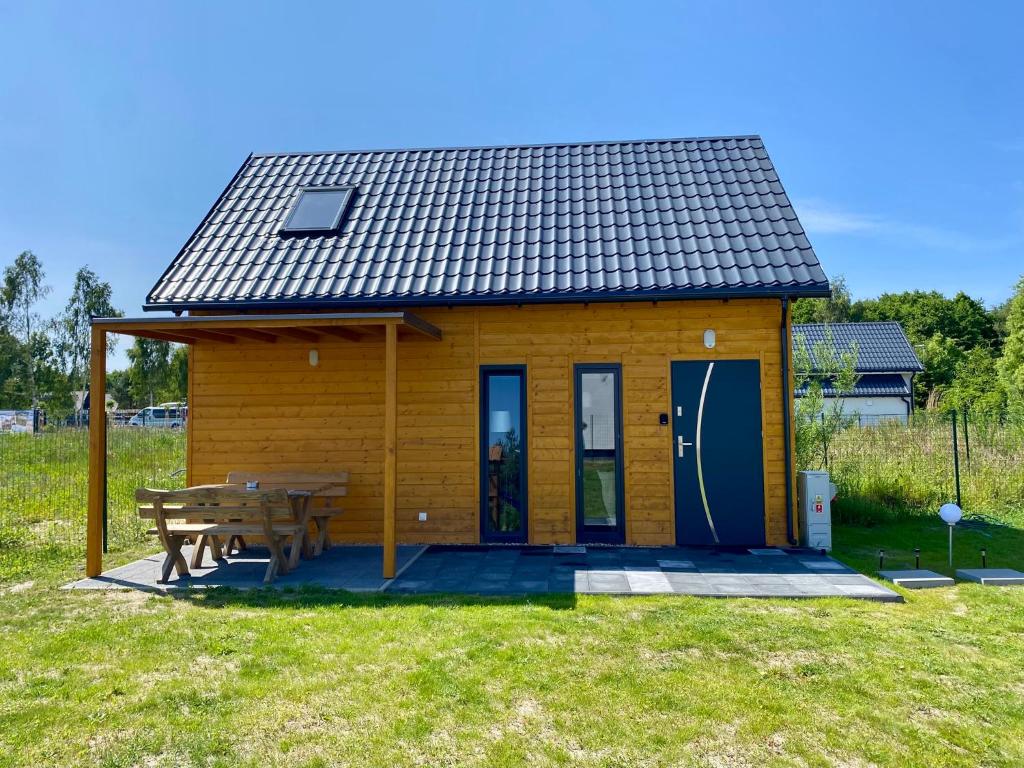 a small yellow house with a picnic table and a bench at Mile domki in Jarosławiec