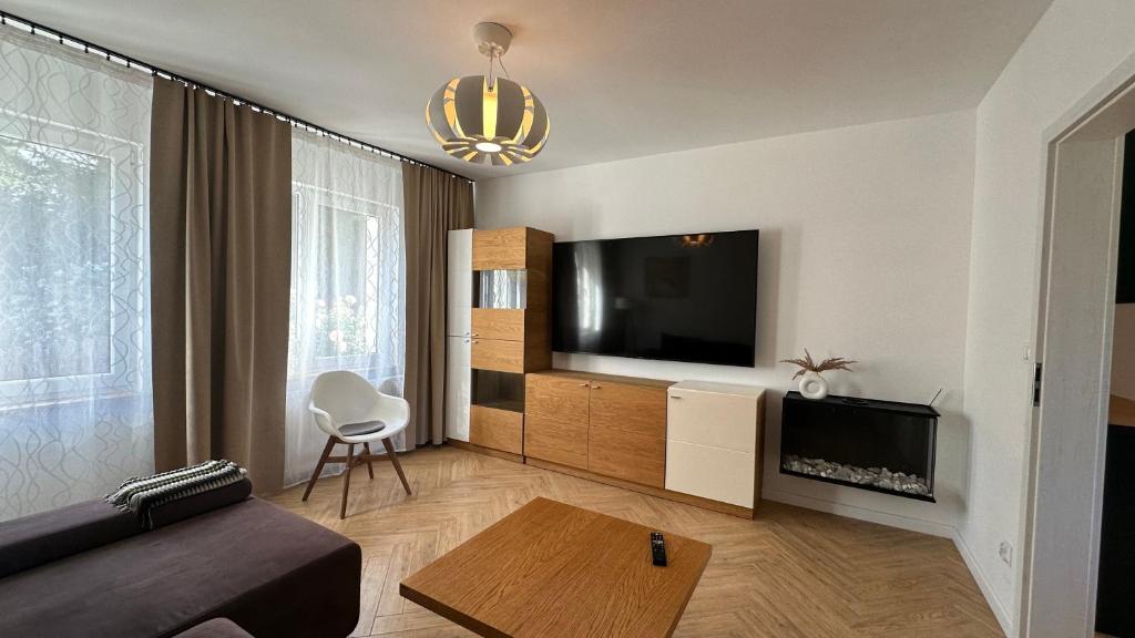 a living room with a couch and a flat screen tv at Dom wakacyjny z basenem i sauną GWIZD Ustronie Morskie in Grąbnica