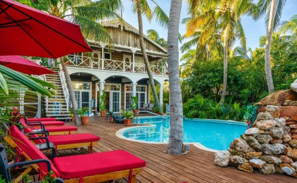 a resort with a swimming pool and red chairs at Caye Caulker Boutique Guesthouse in Caye Caulker