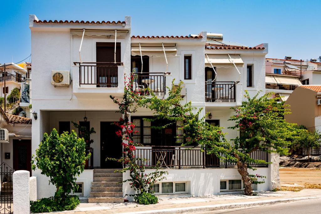 a white apartment building with balconies and flowers at FRINI APPARTMENTS in Kokkari